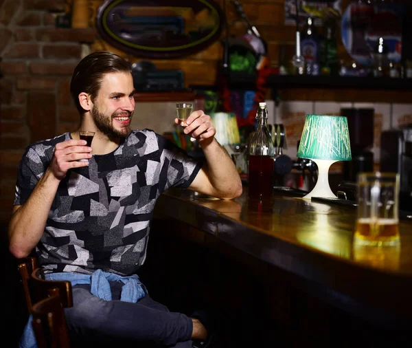 Guy no balcão do bar segura óculos de tiro e rum . — Fotografia de Stock