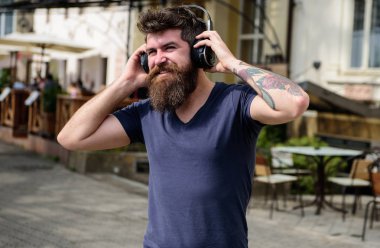 Uzun Sakal ve bıyık kafa, ufuk kentsel arka plan üzerinde kablosuz kulaklık ile olan adam. Yürürken yüz müzik dinleme gülümseyen üzerinde kulaklık ile hippi. Kablosuz teknolojileri kavramı