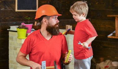 Evlat, çocuk neşeli anahtar anahtarı, baba ile öğrenme kullanım araçları tutar. Baba, üst koruyucu kask okul atölyesinde farklı araçları kullanmak için küçük oğlu öğretim içinde sakallı. Babalık kavramı