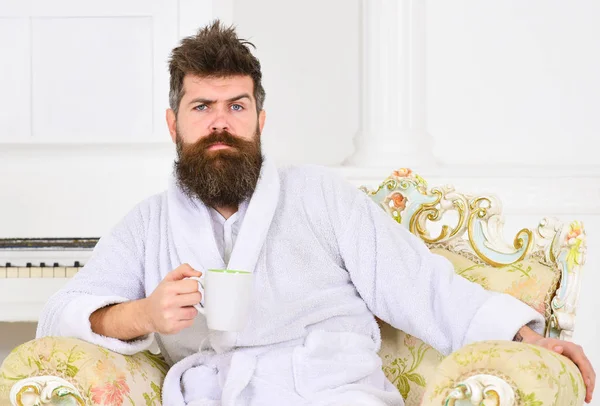 Millionnaire appréciant le café du matin. Guy assis dans une belle chaise sur fond blanc. Homme fronçant les sourcils et levant les sourcils pendant le petit déjeuner — Photo