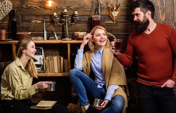 Amigos o familiares pasan una agradable velada en la casa de guardabosques, fondo interior. Familia disfrutar de vacaciones. Concepto de comodidad. Las niñas y el hombre en caras sonrientes disfrutan de un ambiente acogedor mientras descansan —  Fotos de Stock