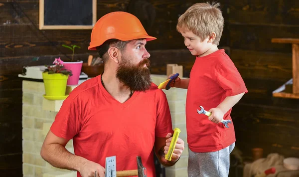 Evlat, çocuk neşeli anahtar anahtarı, baba ile öğrenme kullanım araçları tutar. Baba, üst koruyucu kask okul atölyesinde farklı araçları kullanmak için küçük oğlu öğretim içinde sakallı. Babalık kavramı
