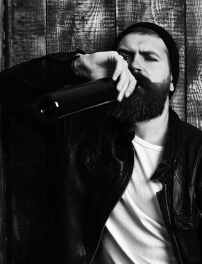 Sakallı vahşi beyaz hippi şişeden içiyor.