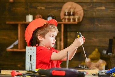 Yan küçük çocuk bağlama vida ahşap pano içine görüntüleyin. Konsantre çocuk tornavida ile oynuyor. Küçük Oluşturucusu'nda atölye