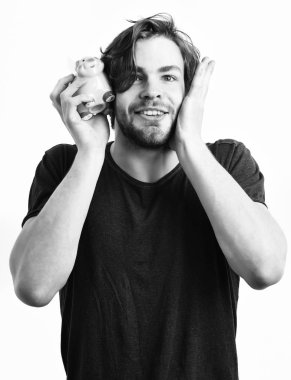 Beyaz seksi genç maço elinde pembe domuz kumbarası tutuyor.