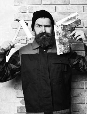 Sakallı ressam ciddi yüzlü çeşitli bina aletleri tutuyor.