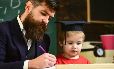 Evde eğitim kavramı. Hevesli çocuk öğretmen ile eğitim. Ödev, çocuk, yardımcı olur kontrol baba evlat. Öğretmen formal giyim ve öğrenci sınıfta kolej, kara tahta arka plan