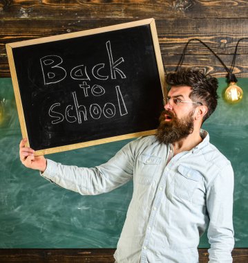 Lise kavramı. Adam sakal ve bıyık sürpriz yüz memnuniyetle öğrencilerin, kara tahta arka plan ile. Gözlük öğretmen okul için başlıklı yazı tahtası tutar