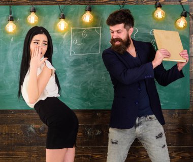 Sakallı, seksi öğrenciyi tokatlayan, arka planda yazı tahtası olan bir adam. Öğretmen, seksi öğrenciyi poposuna kitapla vurarak cezalandırıyor. Çaresiz suratlı kız öğretmen tarafından cezalandırıldı..
