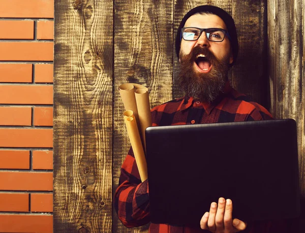 Barbudo brutal caucasiano hipster segurando laptop e papel artesanal — Fotografia de Stock