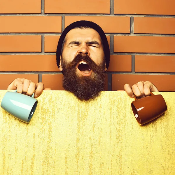 Barbudo brutal hipster caucásico con hoja de papel y tazas —  Fotos de Stock