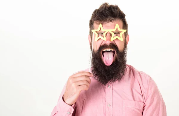 Superstar-Konzept. Mann hält Parteirequisiten sternförmige Brille, weißer Hintergrund. Hipster mit Bart und Schnurrbart auf fröhlichem Gesicht posiert mit sternförmiger Brille und zeigt Zunge, Kopierraum — Stockfoto