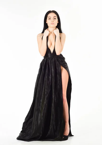 Κυρία, σέξι κορίτσι στο φόρεμα. Γυναίκα σε κομψό μαύρο μακρύ φόρεμα βράδυ με ΝΤΕΚΟΛΤΕ, λευκό φόντο. Η έννοια φόρεμα μόδας. Ελκυστική κοπέλα φοράει ακριβά μοντέρνες βραδινό φόρεμα με σκίσιμο ερωτικό — Φωτογραφία Αρχείου