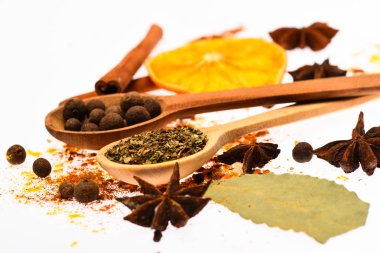 Baharat Seti kavramı. Baharat Seti pişirme veya sıcak içecekler, hazırlama kapatın. Baharat mutfak otlar ve kuru malzemelerle karıştırın. Kaşık, kurutulmuş portakal ve tarçın sopa beyaz arka plan üzerinde