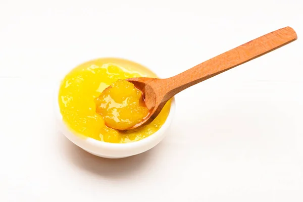 Чаша с желтым органическим медом и деревянной ложкой. Концепция органической пищи. Сладости для здорового питания. Мед в маленькой миске на белом фоне, закрыть — стоковое фото