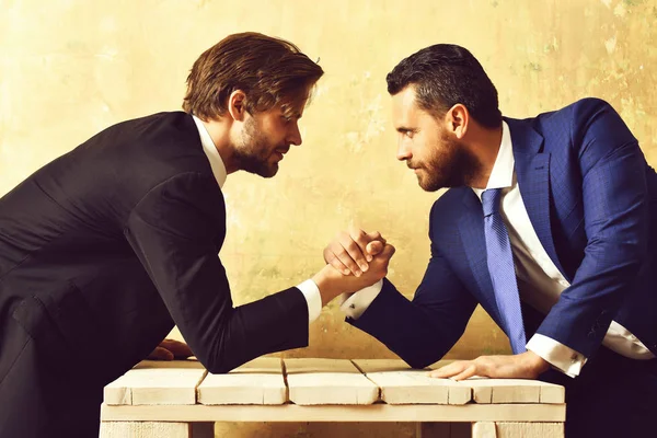 Business competition. Two serious businessmen arm wrestling