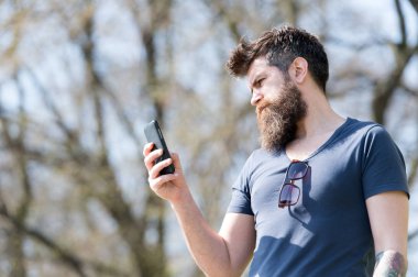 Cep telefonu açık kullanarak sakallı hippi. Sakal ve bıyık katı yüz arama, Doğa arka plan, defocused olan adam. Cep telefonundan mesaj yazarak sakallı adam. İletişim kavramı