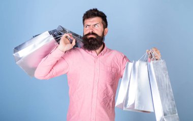 Satış ve indirim kavramı. Satış sezon indirimlerle alışveriş adam. Katı yüz bağımlısı alışveriş veya Alışverişkoliğin hippi. Sakal ve bıyık taşımak alışveriş torbaları, açık mavi renkli olan adam