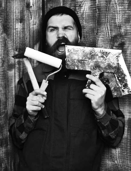 Bearded builder man holding various building tools with satisfied face — Stock Photo, Image