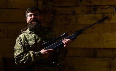Hunter, silahla acımasız hipster tüfek avcılık için kopya alanı hazırlamak. Avcı kavramı. Sakallı kamuflaj elbiseler, ahşap iç arka plan giyer. Maço gamekeepers evinde mutlu yüz