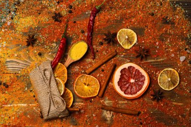 Baharat tüm ahşap yüzey üzerinde dağınık. Tarçın, öğütülmüş kırmızı biber ve curcuma toz ve mutfak otlar dolu kaşık masa üzerinde dağınık. Ahşap doku baharat kaşıklarla. Baharat kavramı.