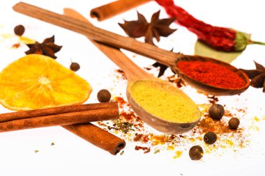 Baharat Seti pişirme veya sıcak içecekler, hazırlama kapatın. Kaşık, kurutulmuş portakal ve tarçın sopa beyaz arka plan üzerinde. Baharat Seti kavramı. Mutfak otlar ve kuru malzemeler ile baharat karışımı