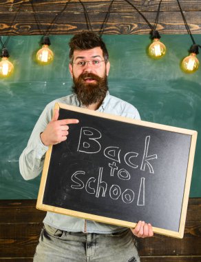 Geri okul kavramı. Adam sakal ve bıyık neşeli yüzü memnuniyetle öğrencilerin, kara tahta arka plan ile. Gözlük öğretmen blackboard yazıt ile geri okula tutar