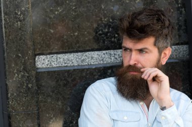 Sakal ve bıyık konsantre yüzünde siyah mermer zemin üzerine olan adam. Adam baktılar ve meraklı görünüyor. Erkeklik kavramı. Tousled saçlı hippi bıyık mesafe içine bakarken katlanmış