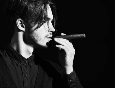 Ciddi sakallı adam puro içiyor.