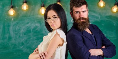 Sakal ve gözlük stand sırt sırta, kara tahta arka plan öğretmen olan adam. Ekip çalışması kavramı. Bayan ve birlikte okulda çalışan hippi. Öğretmen ve öğretmen rahat görünüyor