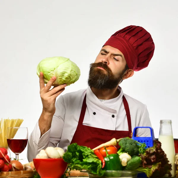 El chef prepara la comida. Cocinar con la cara curiosa en uniforme de color burdeos — Foto de Stock