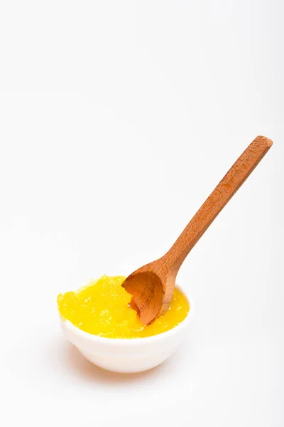 Чаша с желтым органическим медом и деревянной ложкой. Концепция органической пищи. Мед в маленькой миске на белом фоне, закрывай. Сладости для здорового питания — стоковое фото