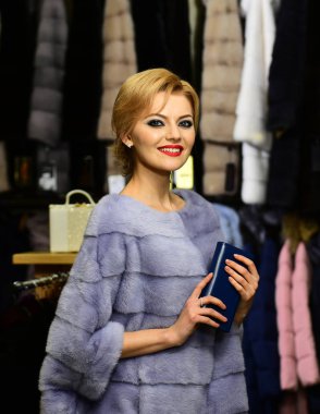 Sarışın kadınla kürklü ceket satın alır. Zengin moda kavramı
