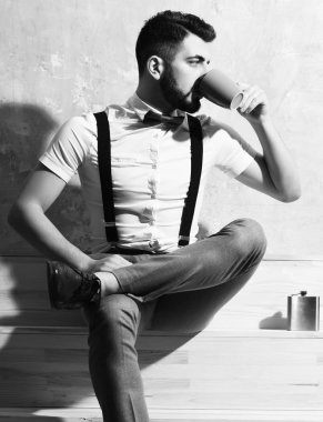 Sakallı adam kahve içiyor, fincandan çay içiyor.