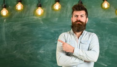 Sakal ve bıyık katı yüz stand önünde kara tahta üzerinde olan adam. Gömlek, arka plan kopya alanı kara tahta sakallı hippi. Yönetim Kurulu, işaret parmağı ile işaret eden adam. Sıkı öğretmen kavramı