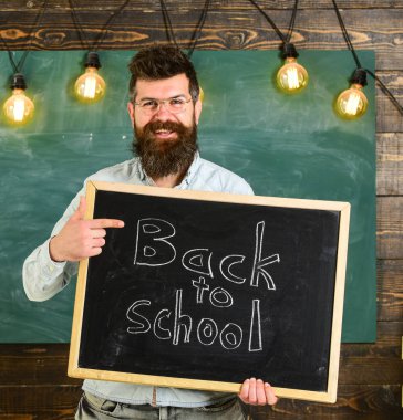 Gözlük öğretmen blackboard yazıt ile okula geri tutar. Sakal ve bıyık arka plan kara tahta gülümseyen yüz memnuniyetle öğrencilerin, üzerinde olan adam. Geri okul kavramı