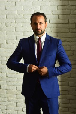 İş adamı resmi takım elbise ve kravat takar. Sakallı lider.