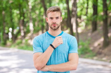 Katı yüzlü sporcu, spor malzemeleriyle poz veren, doğa geçmişi olan biri. Fitness takip cihazı ya da adım sayacı olan bir atlet. Spor aleti konsepti. Adımölçer aygıtıyla sporcu eğitimi