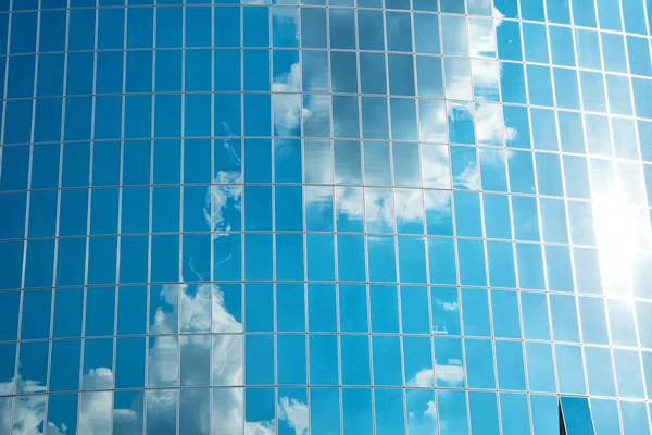 Nuvens refletidas na parede de fachada de vidro do edifício. Reflexão céu azul nublado nas janelas. Arquitetura de vidro moderna. Antecedentes arquitectónicos. estrutura e design. Futuro e desenvolvimento — Fotografia de Stock