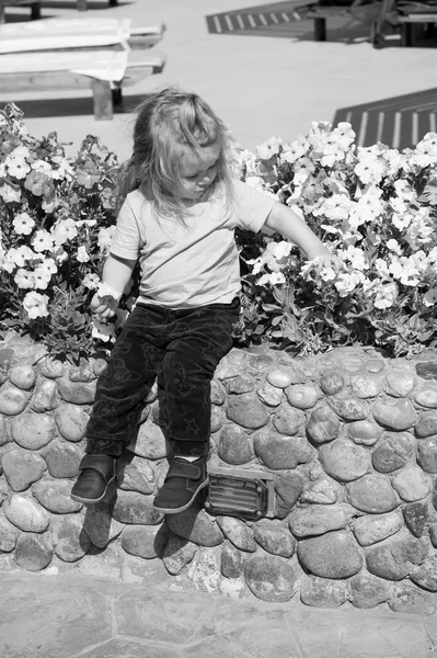 男孩坐在石路边花卉环境 — 图库照片