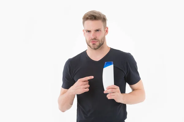 Bearded man point finger at shampoo or gel bottle. Macho with beard in tshirt show cosmetic for bath or shower. Presenting product concept. Hair care and beard grooming. Mens beauty and health — Stock Photo, Image
