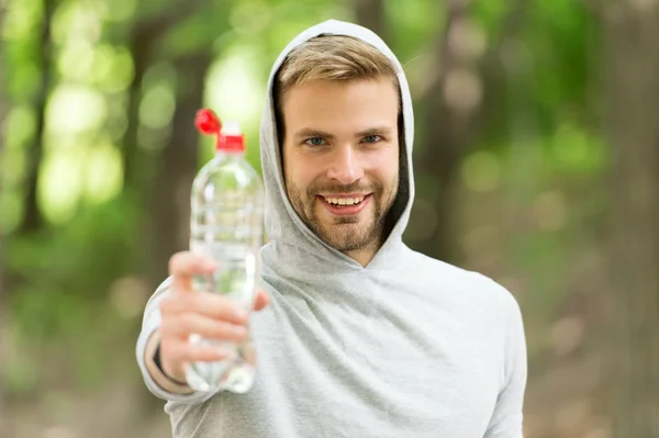 Atletik görünüşlü bir adam şişeyi suyla tutar. Spor kıyafetli erkek sporcu dışarıda antrenman yapıyor. Spor ve sağlıklı yaşam tarzı kavramı. Sporcu eğitimden sonra su içer. — Stok fotoğraf