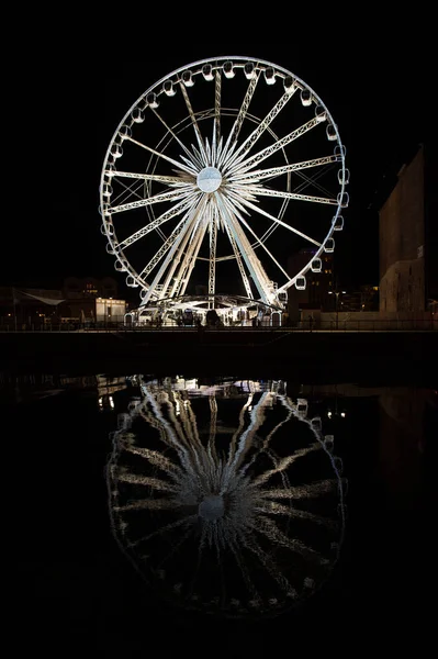 Pozorování kolo v Gdaňsku, Polsko v noci. Rekreační atrakce s osvětlení a reflexe v temné vodě. Vyhlídkové a cestování. Dovolená a toulavost — Stock fotografie