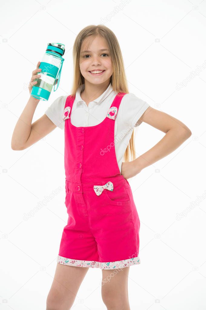 Happy child in pink jumpsuit hold water bottle. Little girl smile with plastic bottle isolated on white. Drinking water for health. Thirst and dehydration. Childhood activity and energy