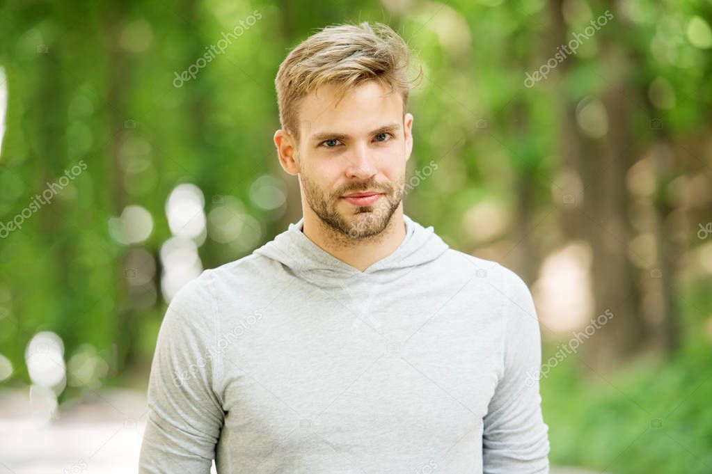 Man with bristle on calm face, nature background, defocused. Skin care concept. Man with beard or unshaven guy looks handsome outdoor. Guy bearded and attractive cares about his appearance