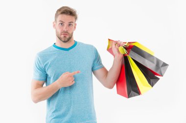 Adam şaşırmış yüzündeki alışveriş torbaları işaret. Alışveriş kavramı. Adam renkli alışveriş torbaları demet tutar. Üstünde siyah Cuma alışveriş adam. Adam çok maddeleri indirim ile satın