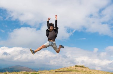 Hippi ya da acımasız Maço dağ fethetti. Adam acımasız görünümü ile atlar. Özgürlük kavramı. Sakallı adam zevk özgürlük, jumpimg dağın zirvesinde. Hipster yürüyüş sırasında gökyüzü arka plan ücretsiz geliyor