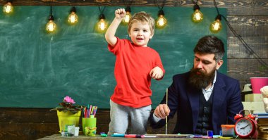 Neşeli çocuk ve resim, çizim öğretmen. Sanat ders kavramı. Yetenekli sanatçı oğlu ile vakit geçirmek. Sakallı öğretmen, babası sınıfta, kara tahta arka plan çizmek için küçük oğlu öğretir.