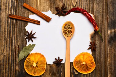 Mutfak tarifi kavramı. Ahşap arka plan üzerinde kağıt parçası. Baharatlar, beyaz kağıt mutfak otlar yatıyordu. Tarçın, kurutulmuş portakal ve biber, Yıldız anason lay boş kağıt, tarifi, çevresinde yer kopyalayın