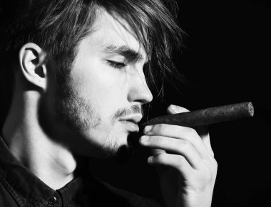 Ciddi sakallı adam puro içiyor.